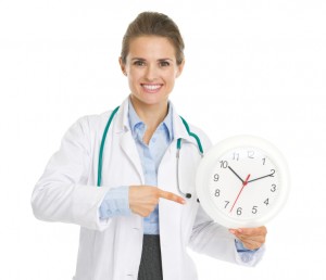 Smiling doctor woman pointing on clock