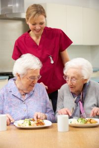 Senior women with carer enjoying meal at home