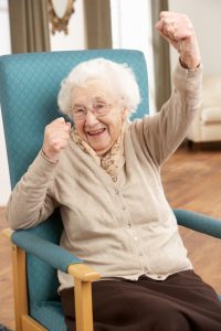 Senior Woman Celebrating In Chair At Home