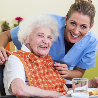 Nurse with senior woman helping with meal