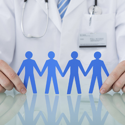 Doctor Holding Blue Paper People Chain At Desk