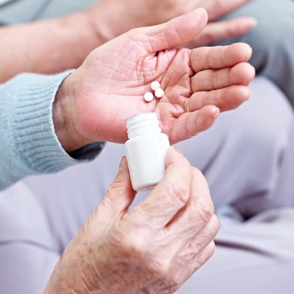A male hand pouring 2 tablets into his hand