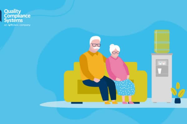 Older couple sitting on a comfy sofa next to a water dispenser in a care setting