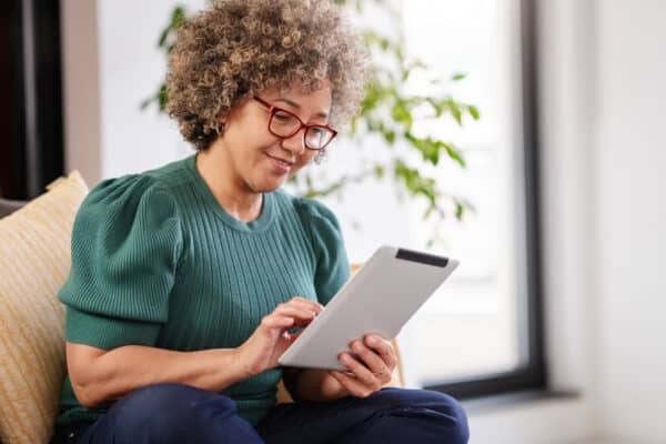 Photo of a woman using a tablet on a sofa